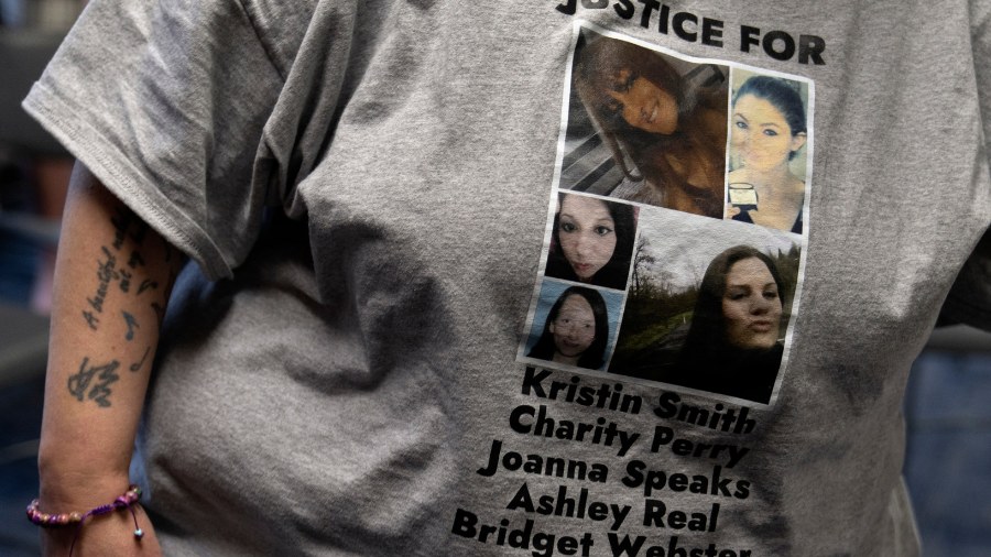 Image: A person wears a T-shirt with the names of Kristin Smith, Charity Lynn Perry, Joanna Speaks,...