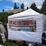 Signs can be seen at a pro-Palestinian tent encampment on the campus of the University of Washington in Seattle on Monday, April 29, 2024. (Photo: James Lynch, KIRO Newsradio)