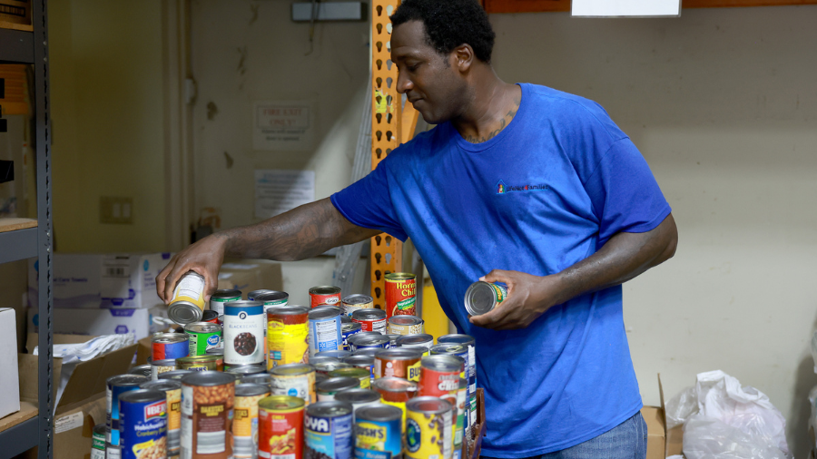 Image: Washington Louis sorts through cans of food at the LifeNet4Families community-based food pan...