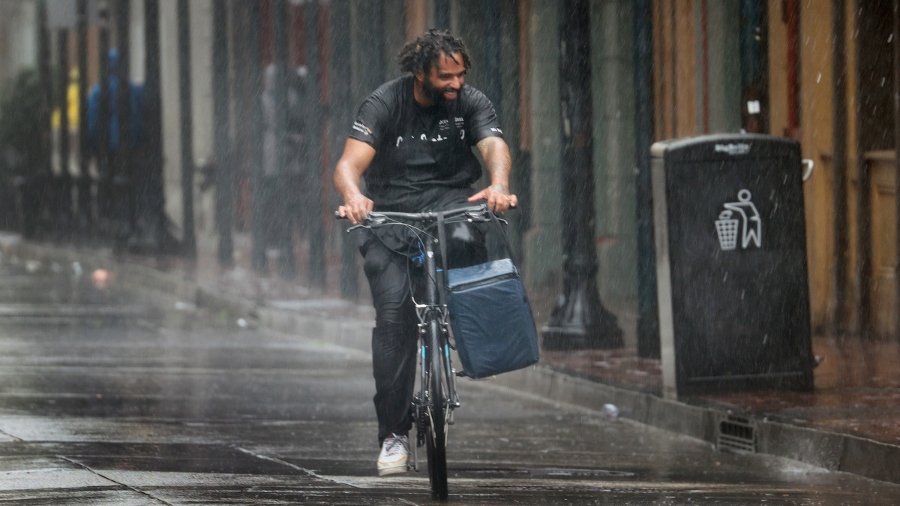 Image: A biker making a food delivery biker grapples with the rain....